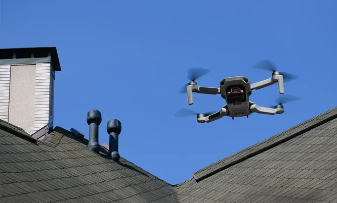 Drohne im Flug über einem Gebäudedach zur visuellen Erfassung und Inspektion von Gebäuden, Bauwerken und technischen Anlagen.